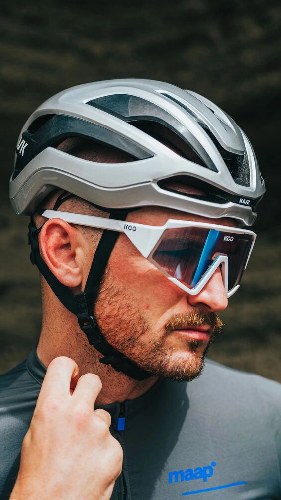 Detail helmy KASK Elemento z boku s popruhy a brýlemi na hlavě vousatého jezdce