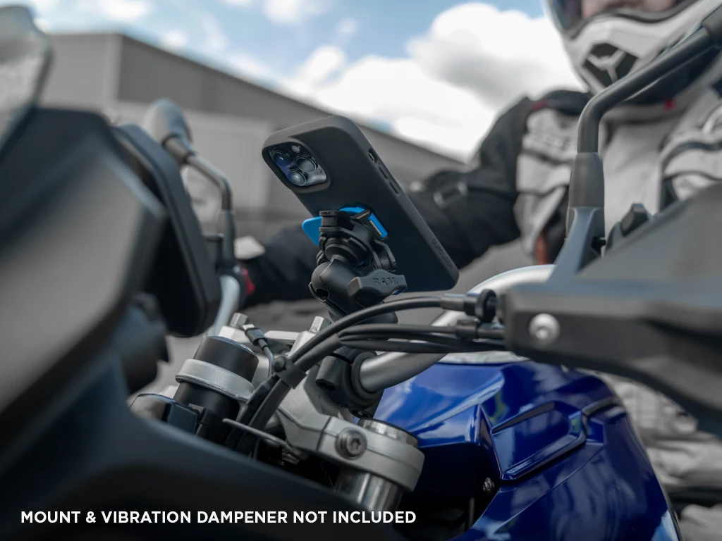 Jezdec v helmě na modrém motocyklu, před ním telefon v pouzdře Quad Lock na adaptéru s tlumičem vibrací v rameni u řídítek (pouzdro, tlumič vibrací a rameno se prodávají zvlášť)