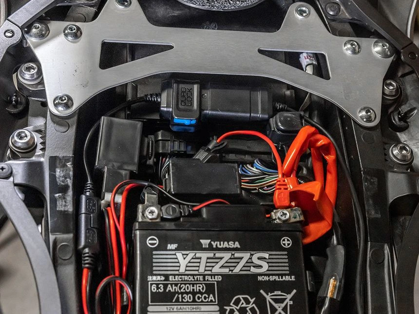 Kabelová oka adaptéru Quad Lock připojená ke svorkám baterie motocyklu