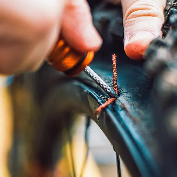 Vkládání knotu vidličkou Peaty's Holeshot Plugger do průrazu bezdušového pláště u ráfku