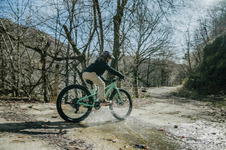 Orbea Kimu 24 H10 projíždí kaluží na lesní cestě
