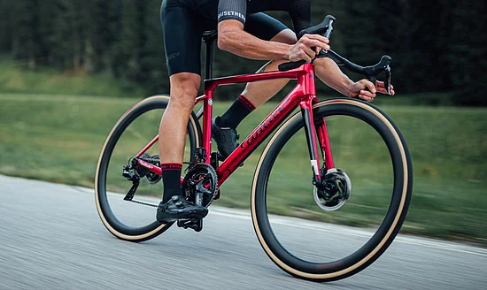 Cyklista jede na kole Wilier Filante SLR po silnici podél louky