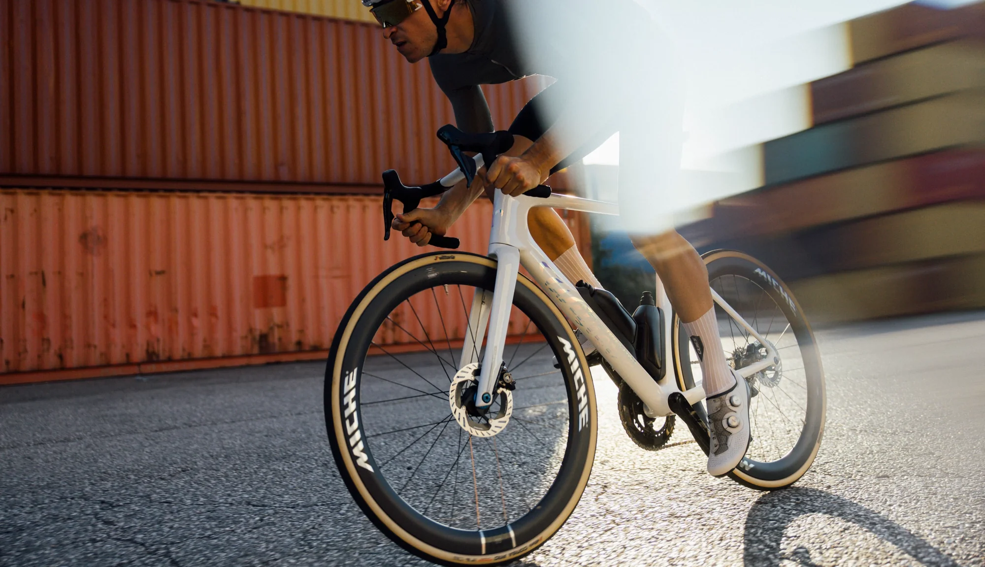 Jezdec na kole Wilier Filante SLR ID2 ve sprintu mezi kontejnery v přístavu