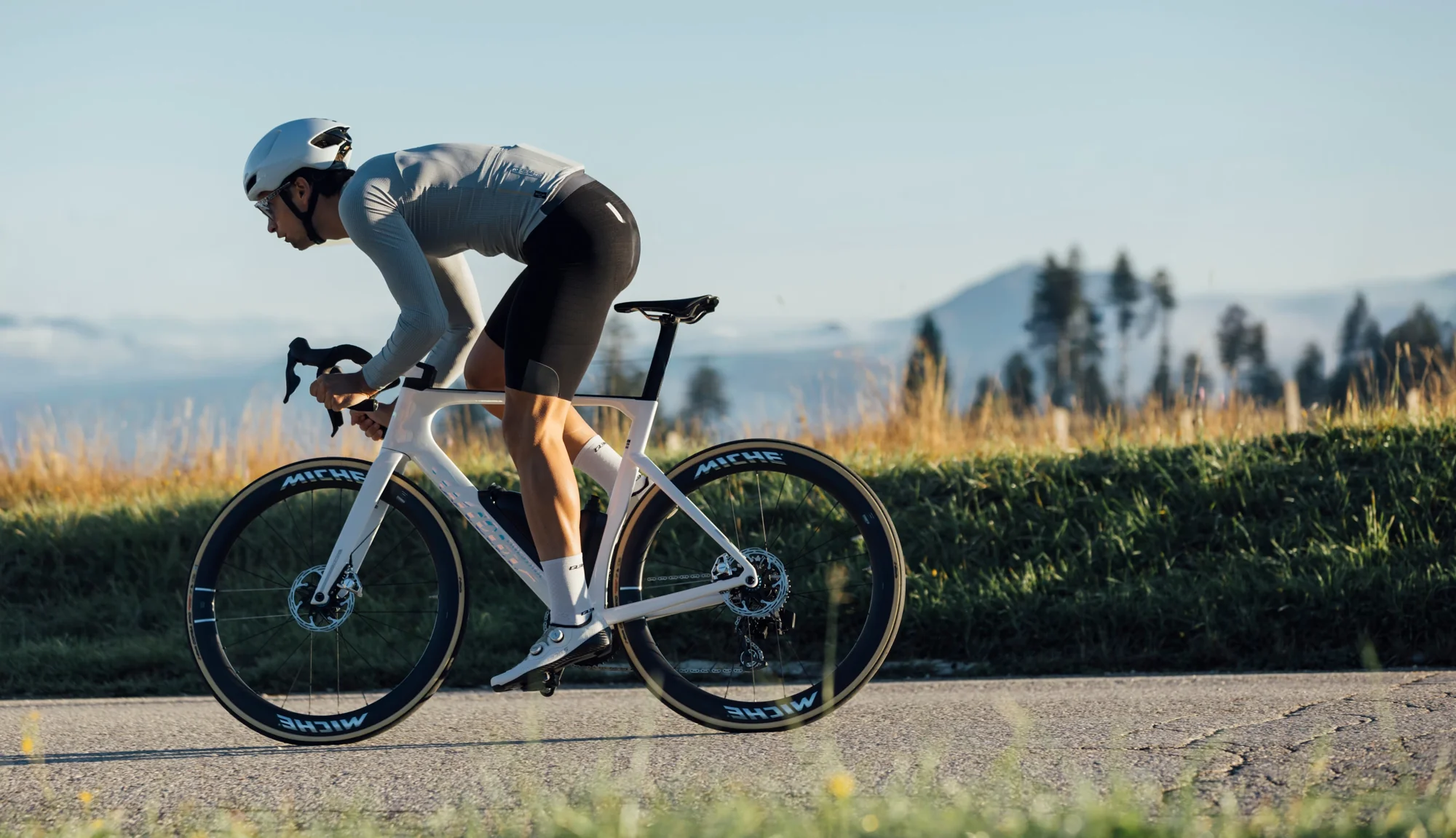 Jezdec na kole Wilier Filante SLR ID2 na silnici, v pozadí hory a stromy
