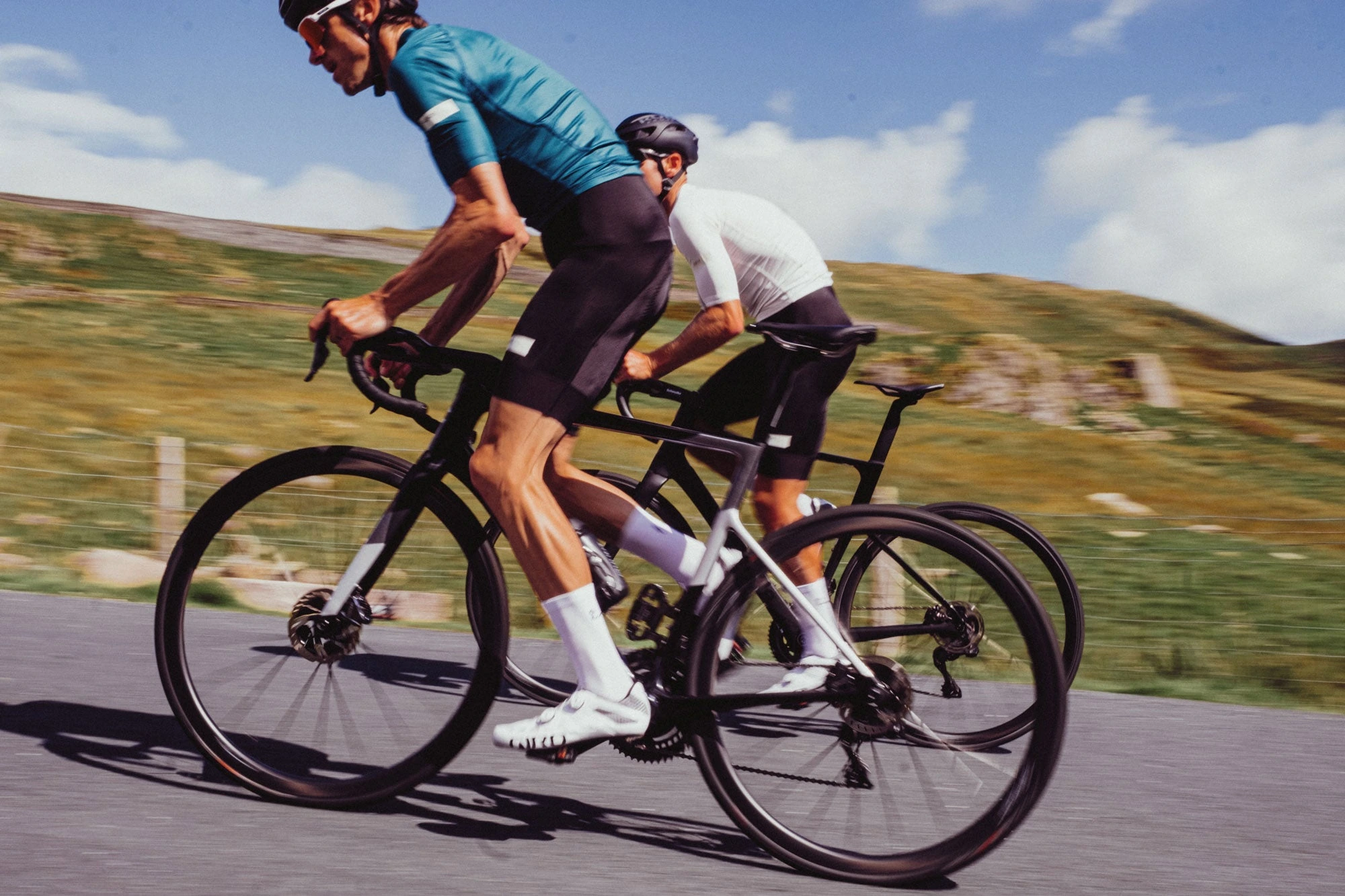 Dva jezdci na silničních kolech s koly HUNT Hill Climb SL Disc Tubular při jízdě po asfaltu v pahorkatině