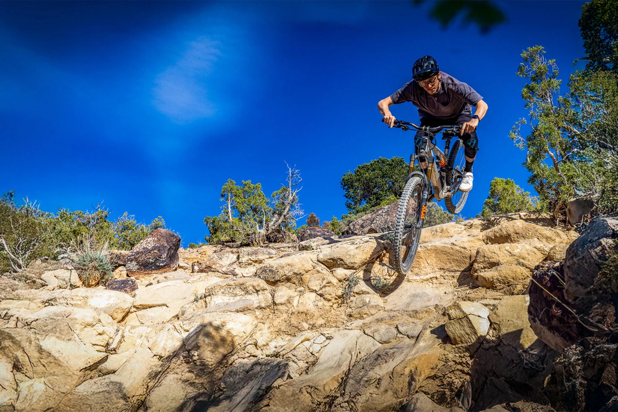 Jezdec na horském kole sjíždí skalnatý terén, zapletená kola HUNT Proven Carbon Enduro H_Core V3 MTB Mullet
