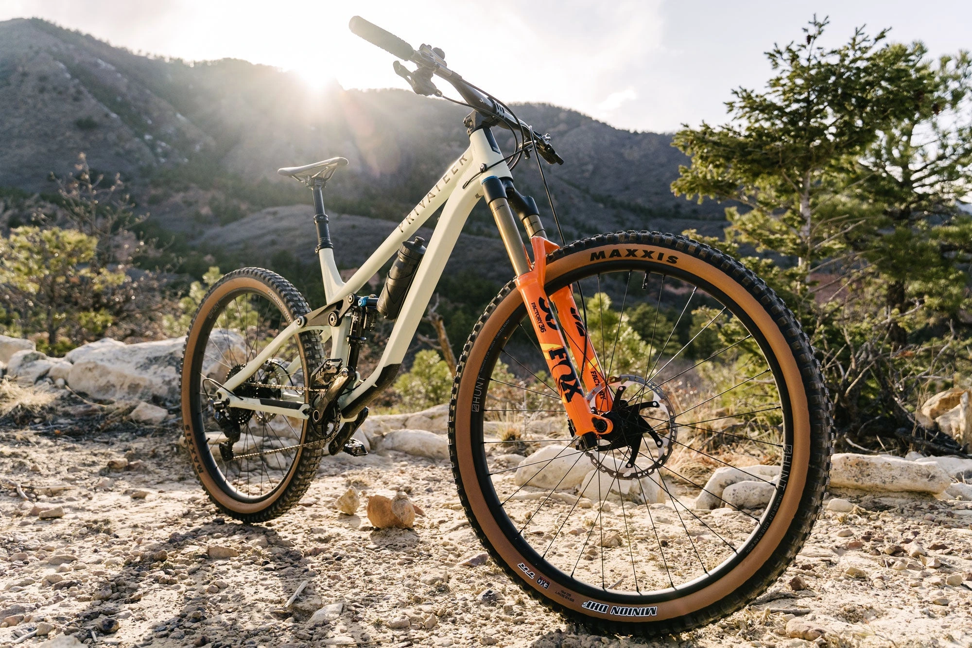 Celoodpružené horské kolo Privateer se zapletenými koly HUNT Trail Wide MTB Mullet na štěrku v horách