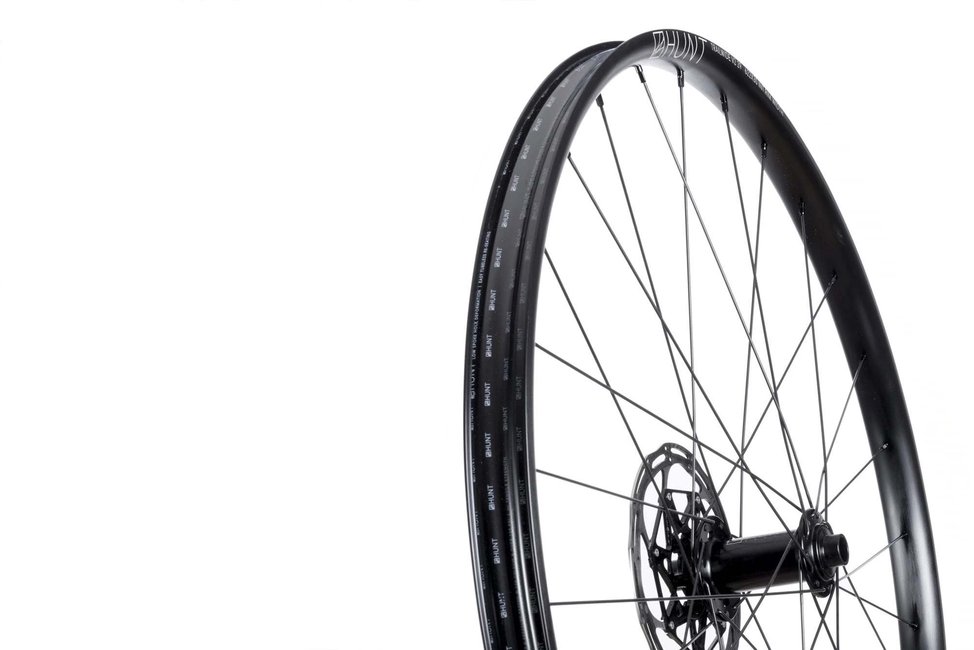 Přední kolo HUNT Trail Wide MTB Mullet s brzdovým kotoučem, šikmý pohled na ráfek s nápisem HUNT