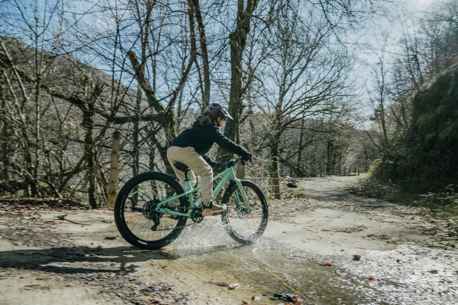Orbea Kimu 24 H10 projíždí kaluží na lesní cestě