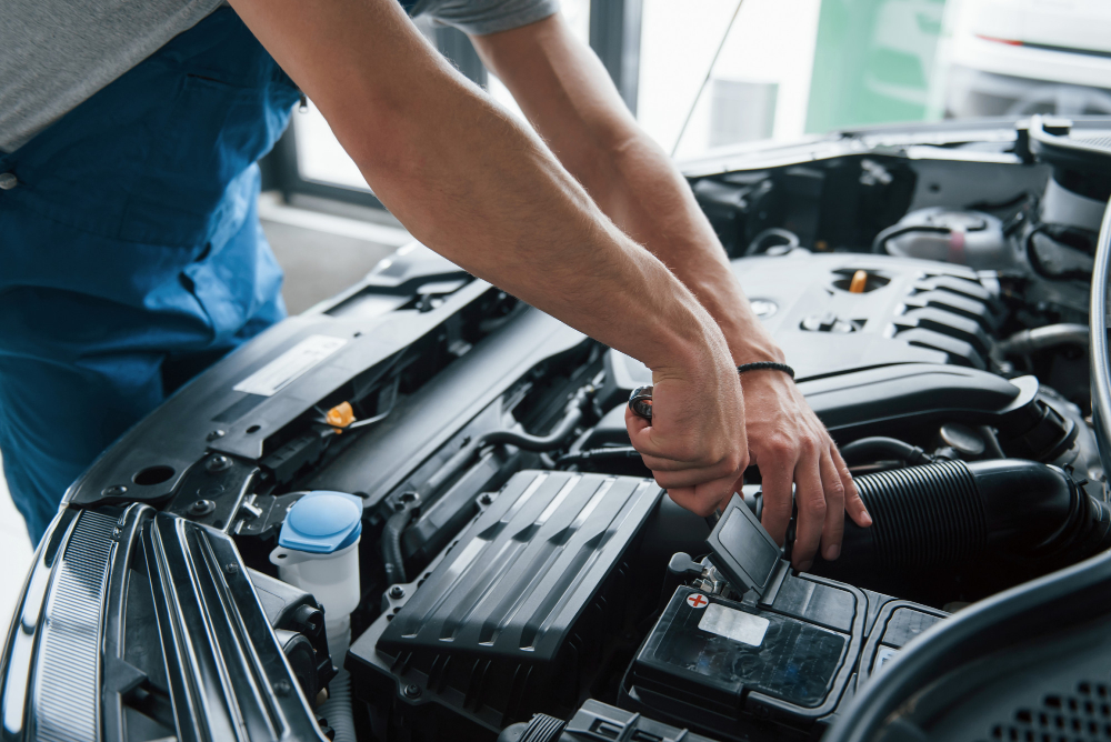 Mechanik provádí kontrolu a nabíjení autobaterie pomocí nabíječky autobaterií v motorovém prostoru vozu.