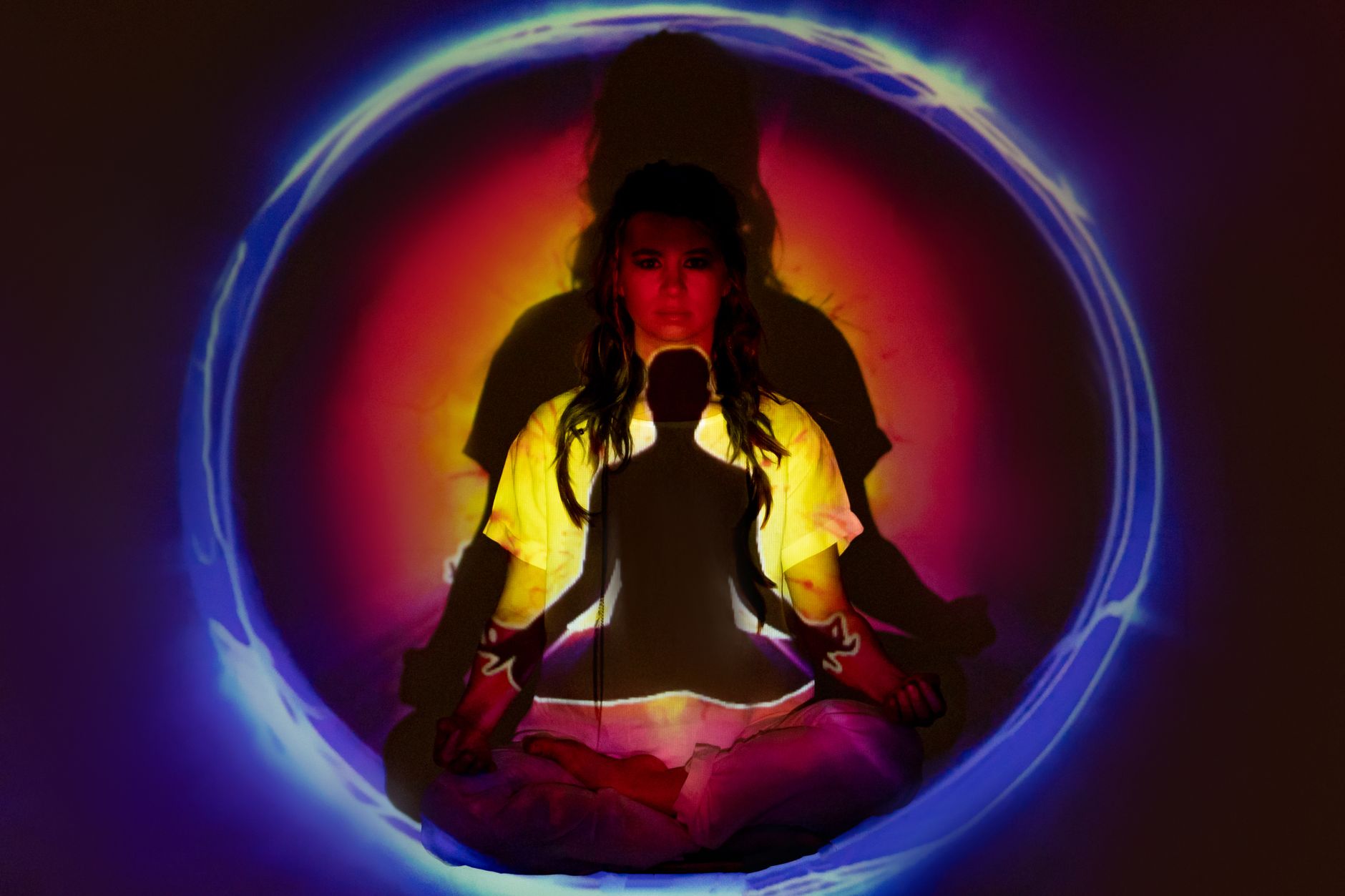 Žena u meditaciji okružena obojenim svjetlom