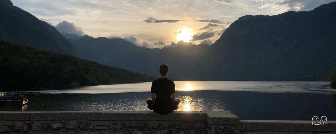 Meditáló alak tóparton, naplementében