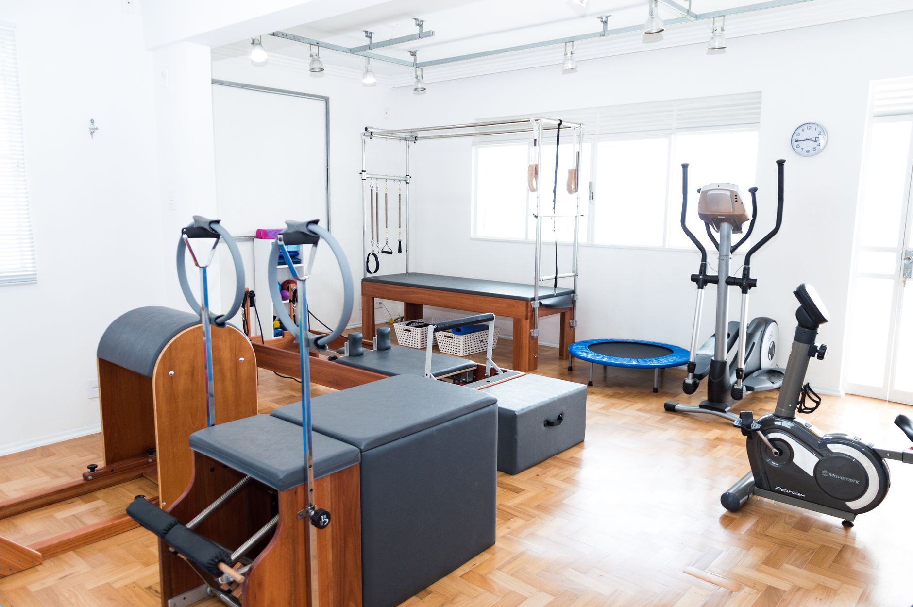 Svetlé Pilates štúdio s drevenou stoličkou a ďalším vybavením