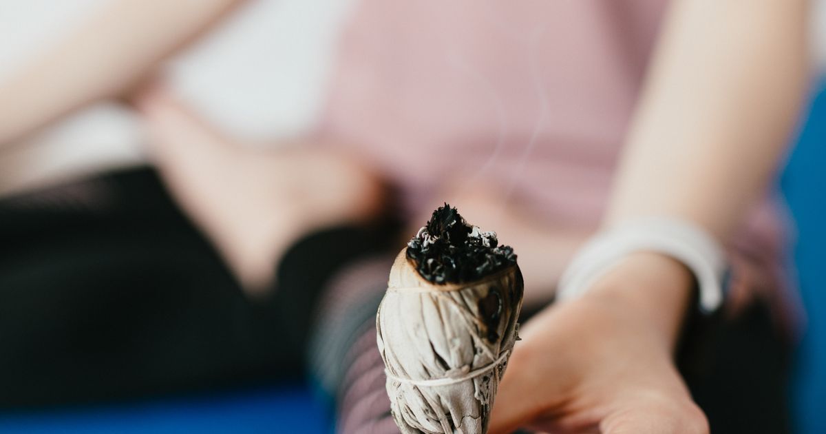 Zväzok bielej šalvie (Salvia apiana) s tlejúcim koncom a stúpajúcim dymom na svetlom podklade