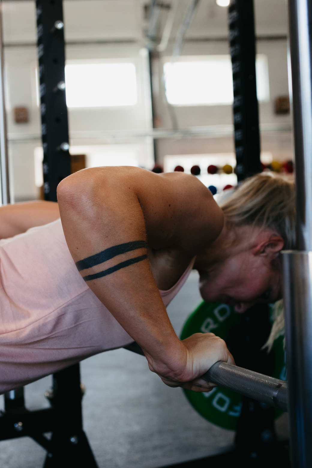 Žena cvičiaca tricepsové kľuky o tyč v multipresse