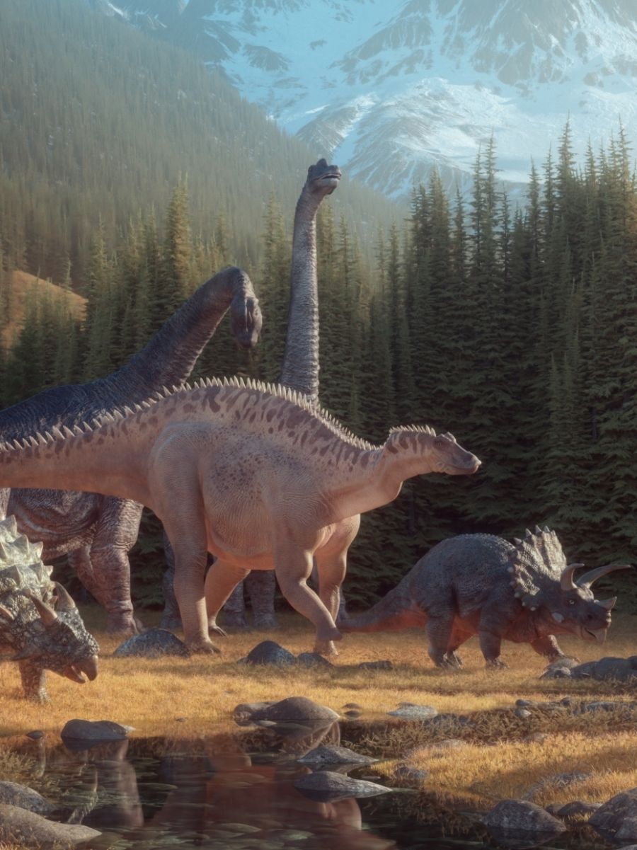 Skupina různých dinosaurů kráčí pravěkou krajinou s bujnou vegetací a horami v dálce.