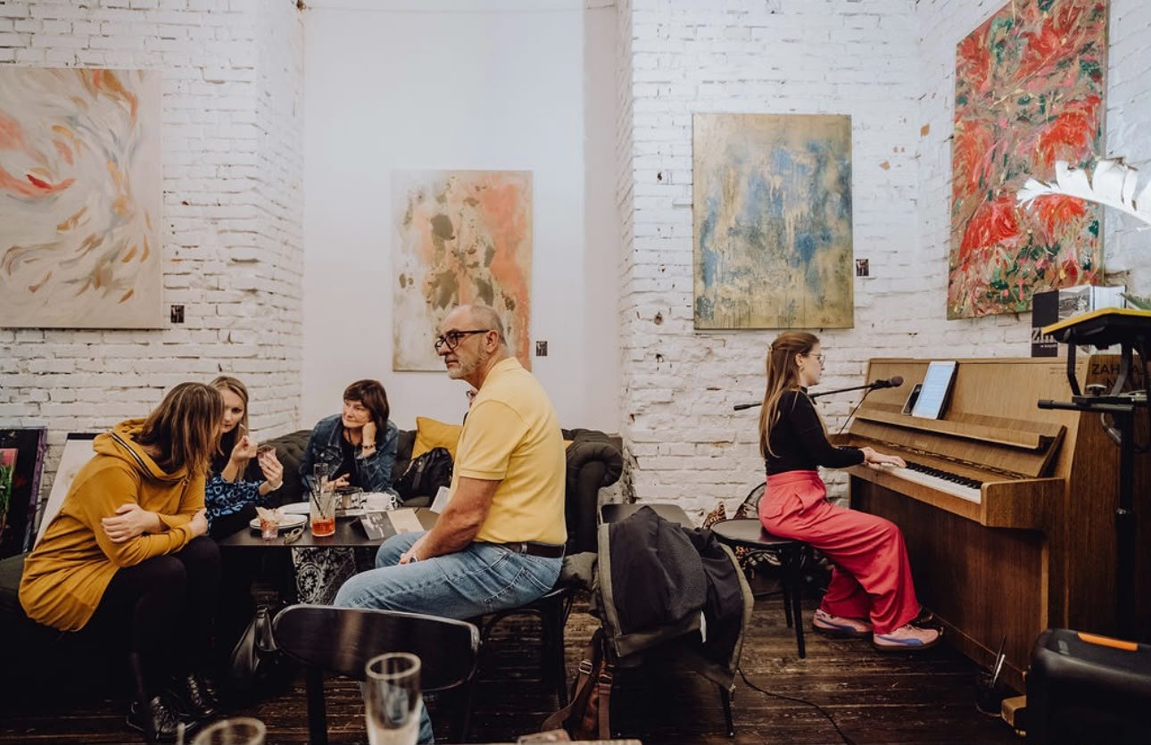 Posezení u klavíru obklopené obrazy Ilony Fryštákové
