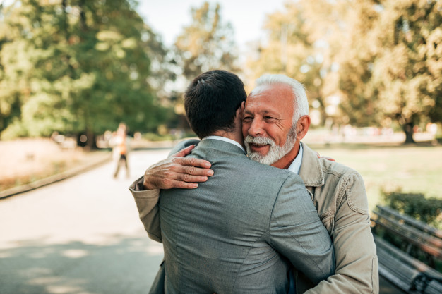 elderly-father-adult-son-hugging-park_109710-400