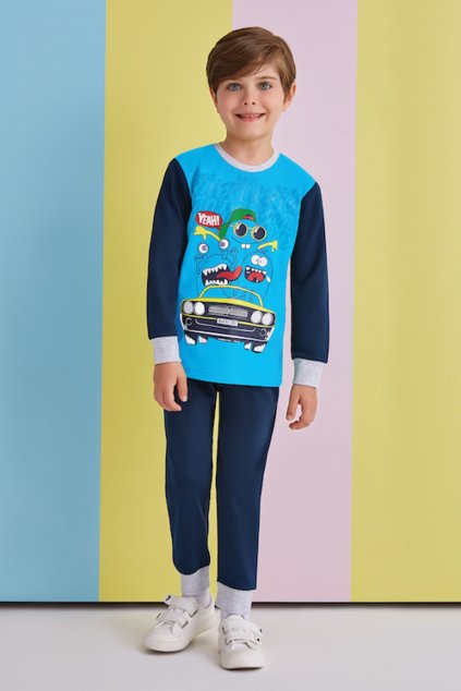Chlapčenské pyžamo s modrým tričkom a potlačou áut, model stojí pred farebným pozadím