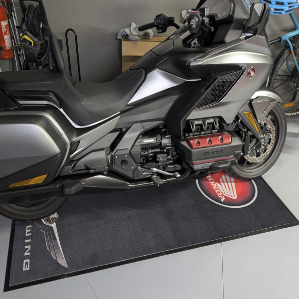 Moto koberec s logom pod motorkou v garáži