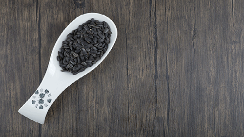 white-spoon-full-healthy-black-sunflower-seeds-placed-wooden-table