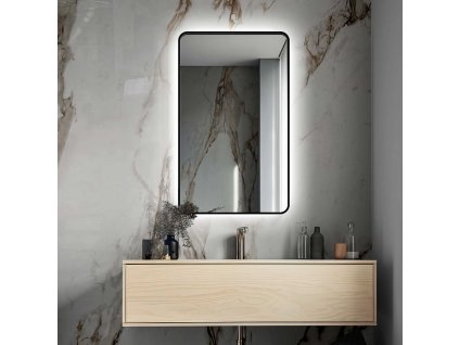 Osvětlené zrcadlo Billet v černém rámu v koupelně nad umyvadlem na pozadí kamenné stěny.