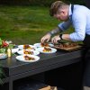 Příprava pokrmů na pracovní desce venkovní kuchyně OFYR Island Black 85 Teak Wood.