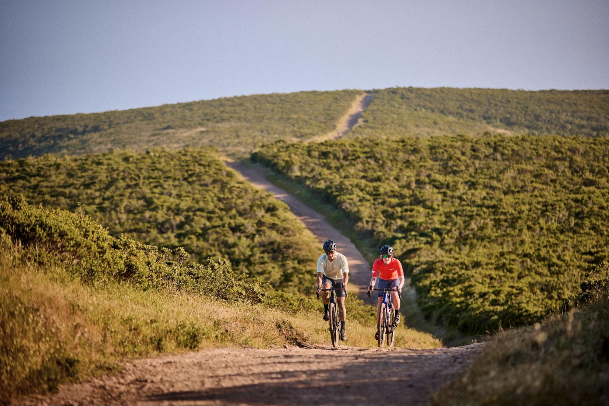 Dvaja jazdci si to berú po prašnej šotoline na gravel bicykloch
