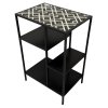 Malý černý kovový odkládací stolek s poličkami a vrchní deskou zdobenou bílými vzory.