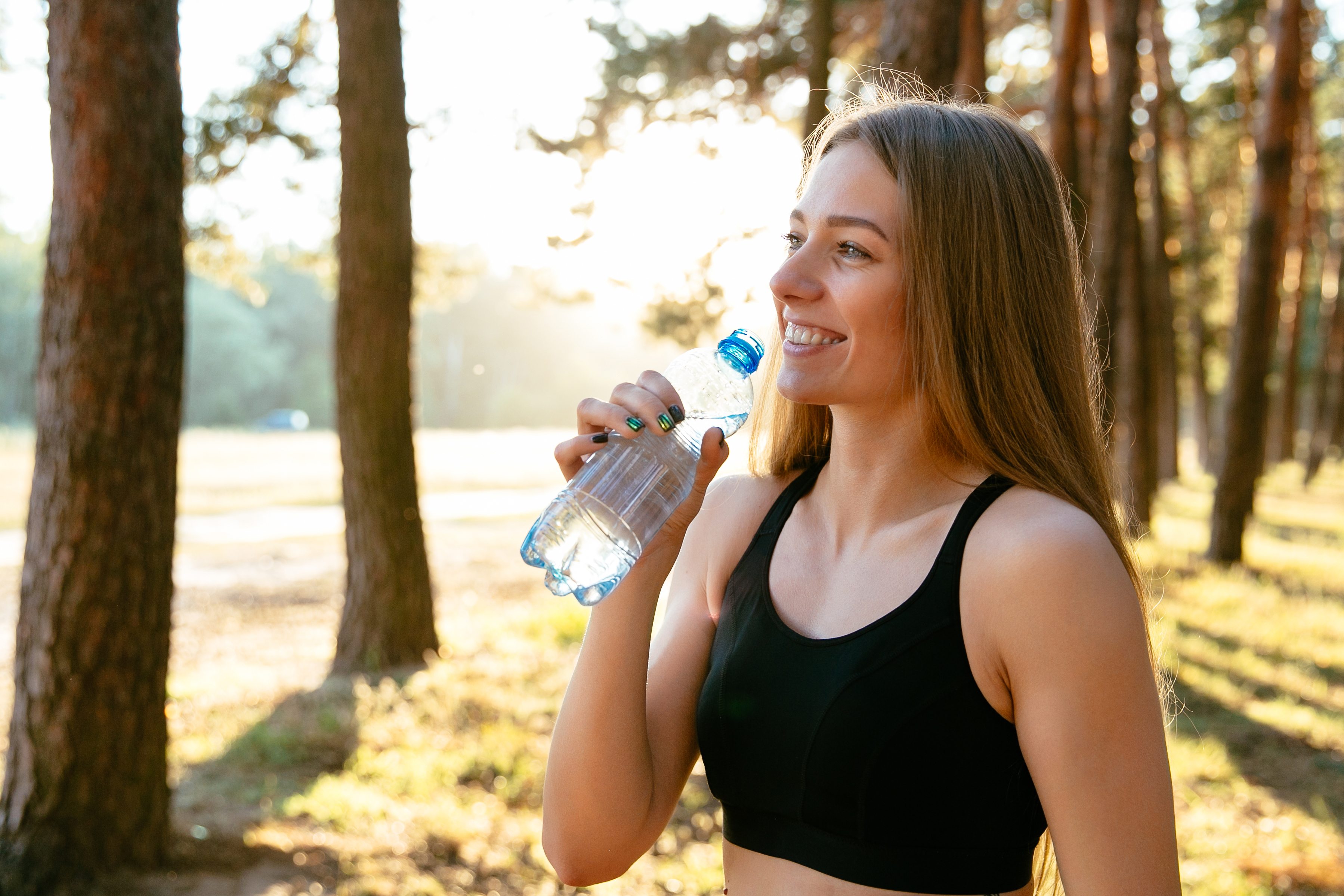 cheerful-amazing-woman-drinking-water-from-bottle-after-workout-park-outdoors