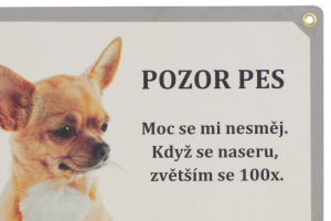 Laminovaná cedulka s ovory na připevnění – „POZOR PES. Moc se mi nesměj. Když se naseru, zvětším se 100×“. Rozměry 21,5 cm × 15,5 cm. (2)