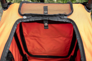  Kočárek pro psy s 38cm kolečky a nosností až 30 kg. Rozměry kabiny 72 × 45 × 60 cm, možnost připevnění upravovacího stolku. Barva černo-oranžová. Detail otevřené horní strany.