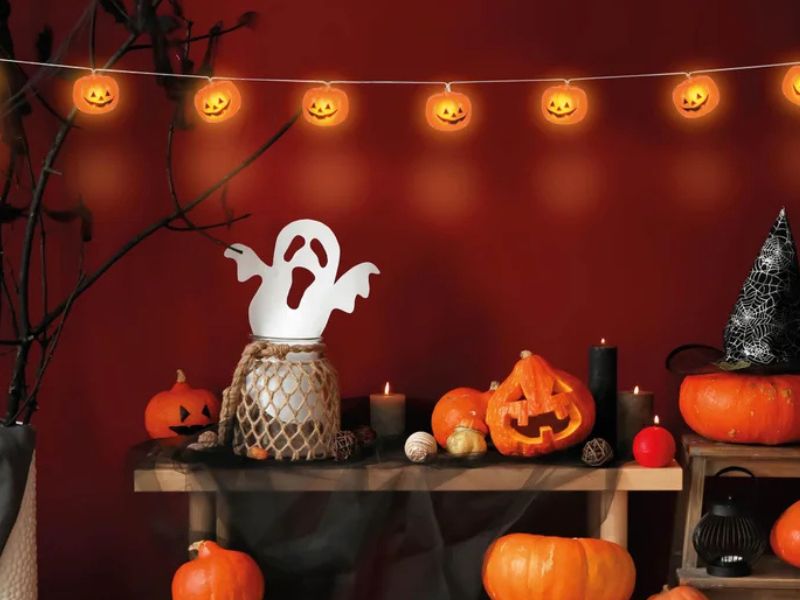Dýně na lavičce s duchem a halloweenskou girlandou.