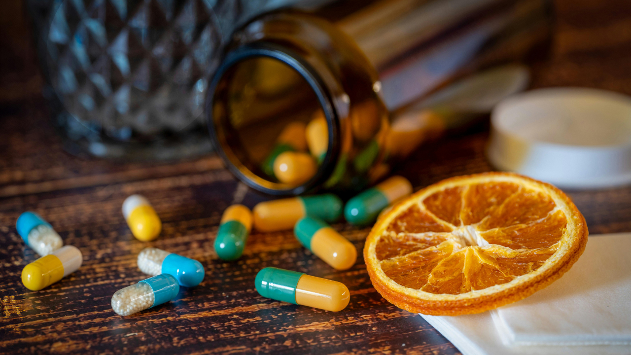 pilulky, fľaška s vitamínmi a ovocie na stole