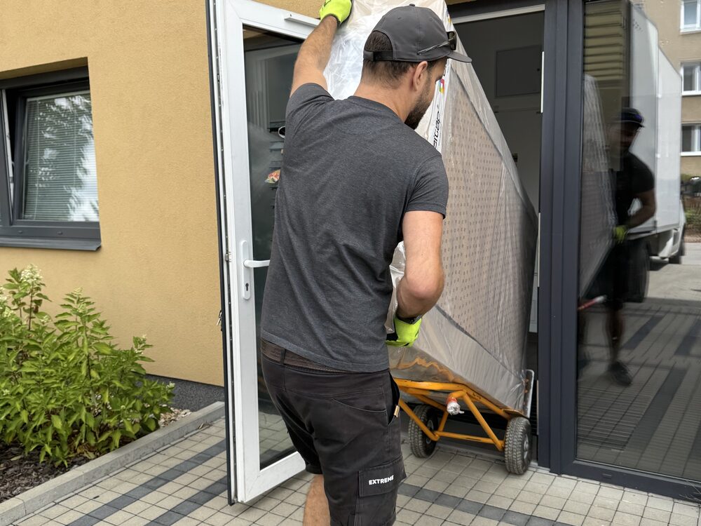Řidič veze zabalený nábytek na rudlu za první uzamykatelné dveře domu