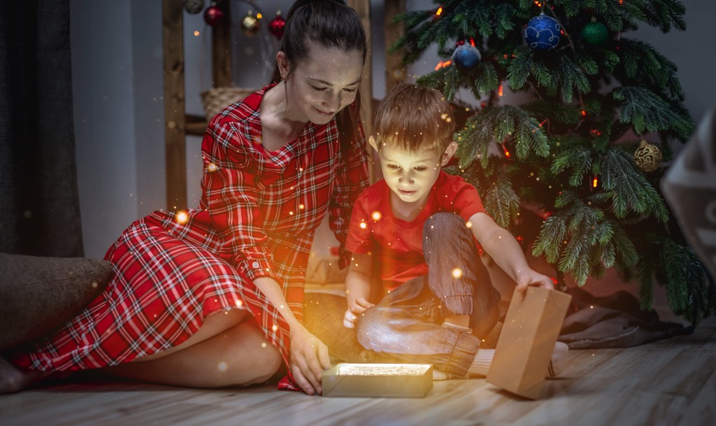woman-little-boy-red-clothes-are-sitting-christmas-tree-joyfully-opening-gift-box-from-which-magical-light-shine-resized