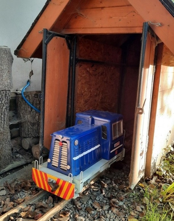 Modrá lokomotiva v dřevěné kůlničce na zahradě