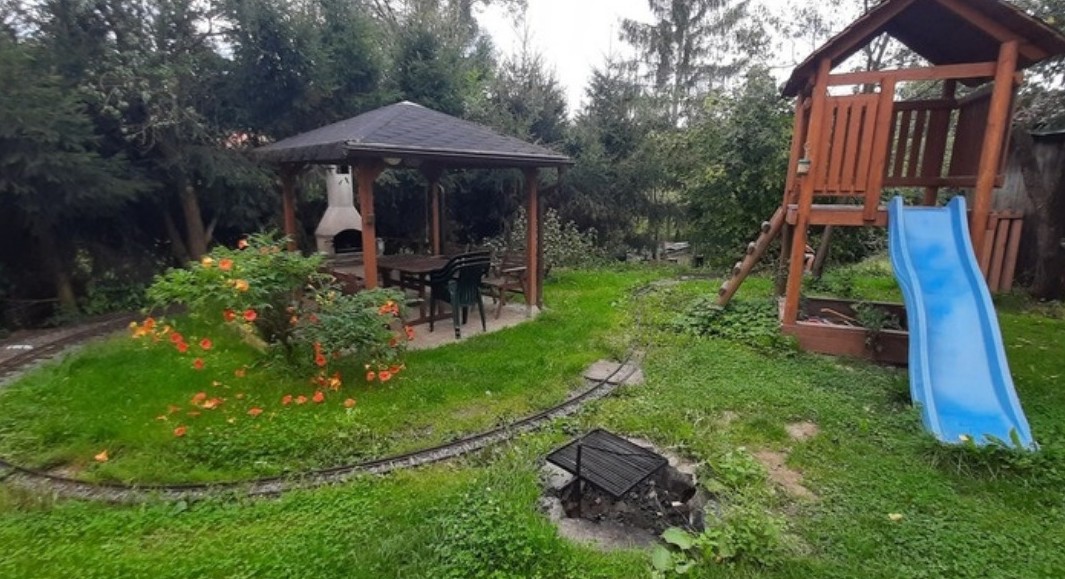 Zahrada s pergolou, ohništěm, skluzavkou a kolejemi