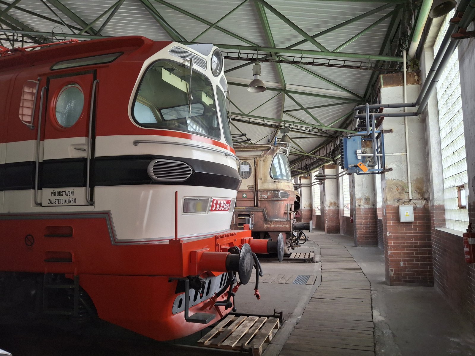Červenobílá elektrická lokomotiva v železničním depozitáři NTM Chomutov