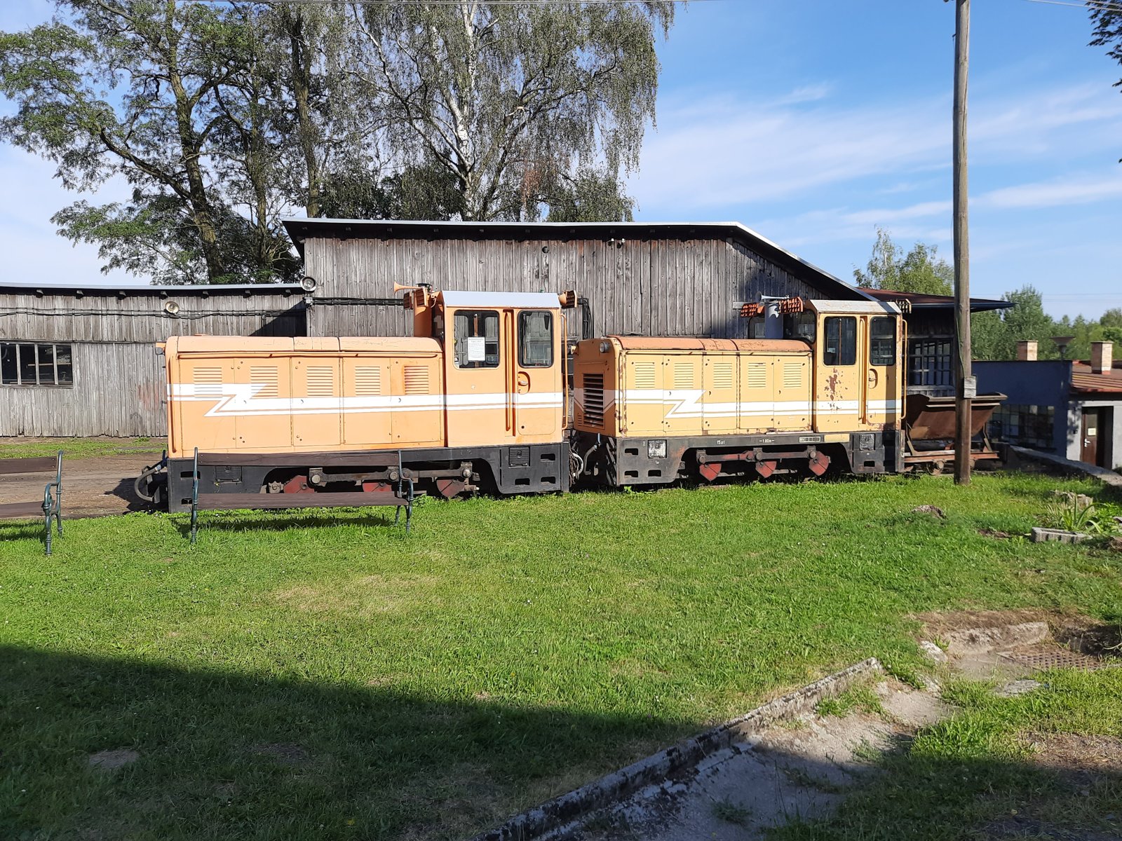 Dvě oranžové motorové lokomotivy před dřevěnou halou
