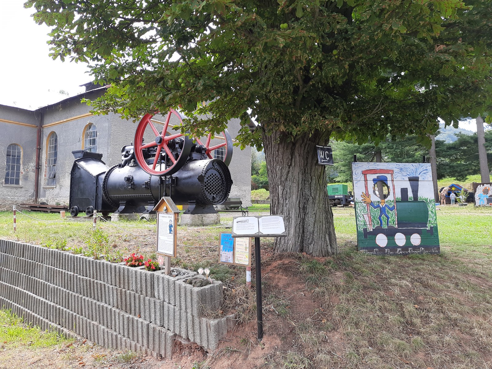 Parní stroj a malovaná fotostěna s lokomotivou v areálu muzea v Mladějově