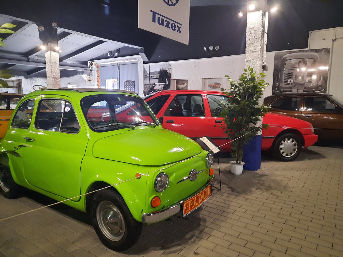Zelené malé auto a další vozy v expozici Retroautomuzea