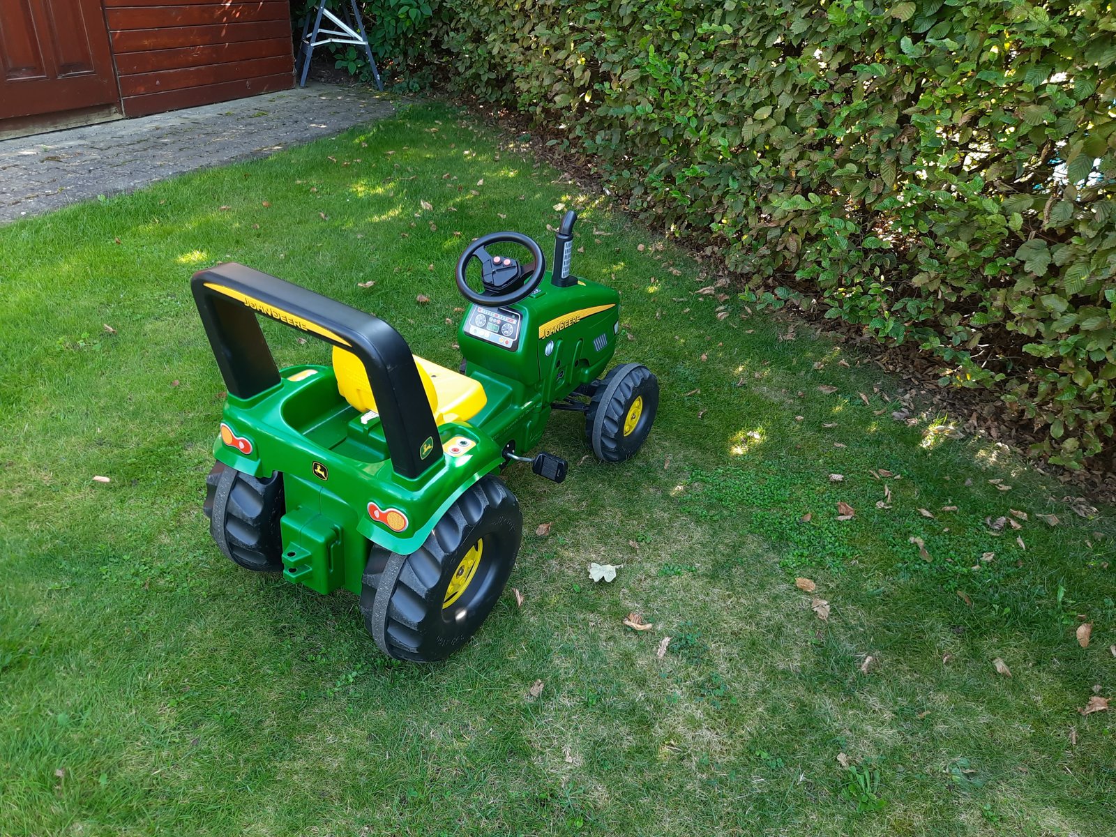Zelený šlapací traktor na trávníku u dopravního hřiště