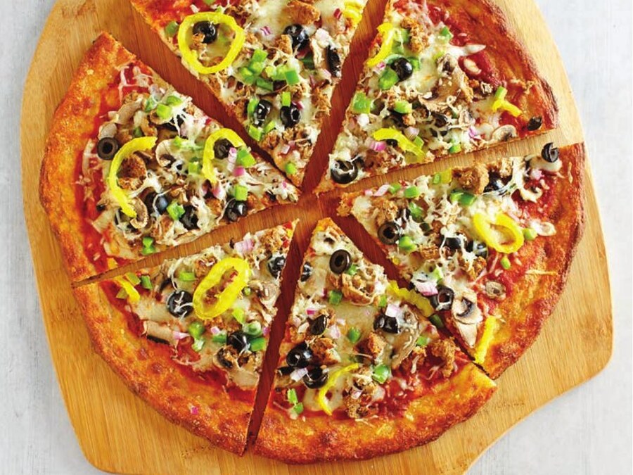 Keto pizza gourmet na dřevěné lopatě, pečená na těstě z knihy Keto pečivo
