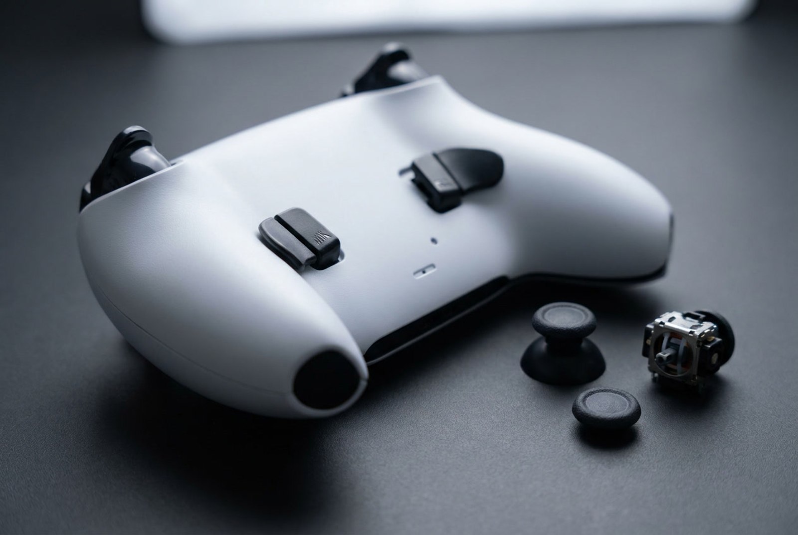 Renovovaný ovládač na PS5 Sony DualSense Edge – detail zadných tlačidiel, posuvníkov spúští, vymeniteľných čiapočiek a modulu páčky