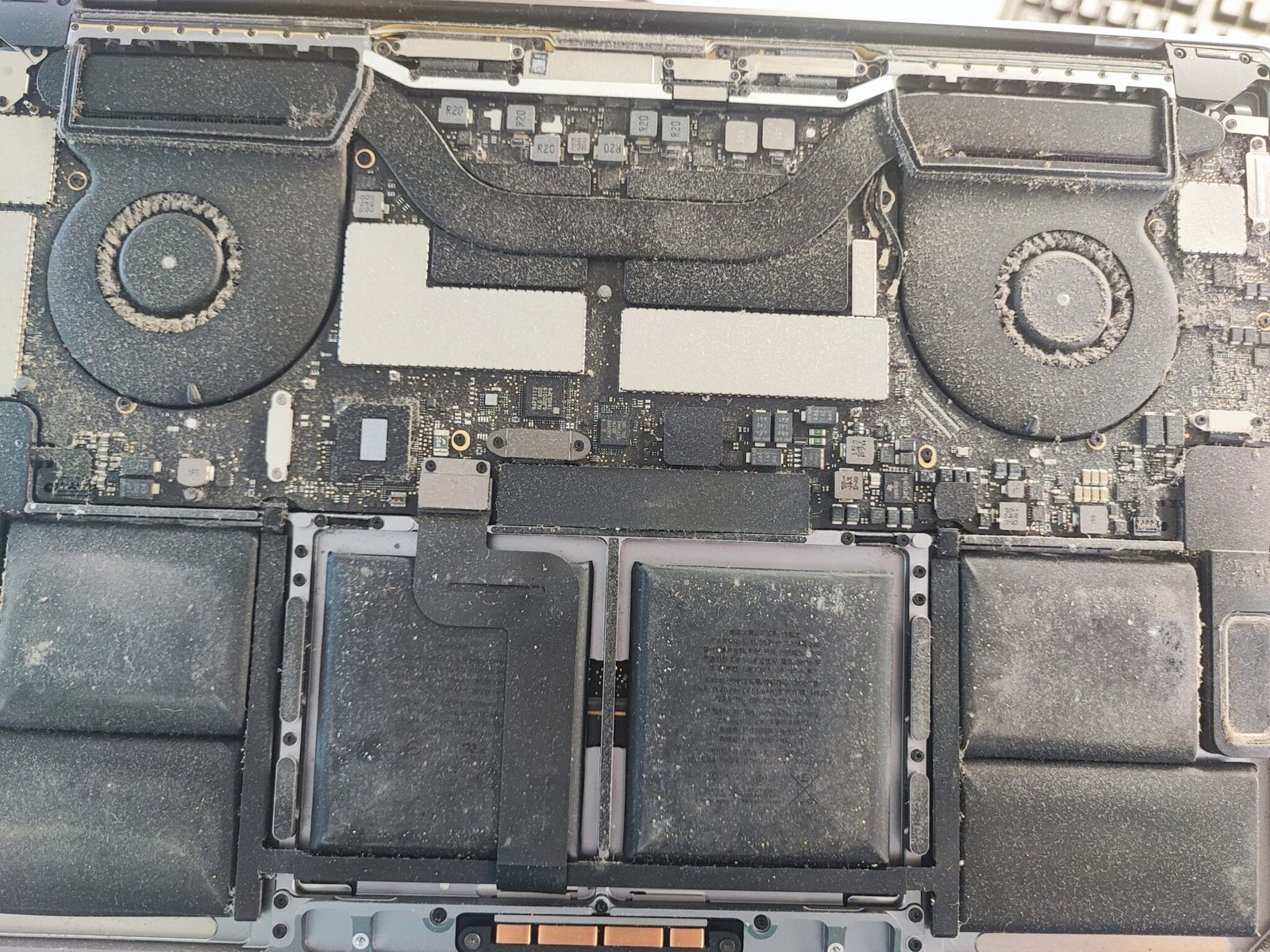 Zanesený MacBook – ventilátory a chladič plné prachu pred čistením a profylaxiou