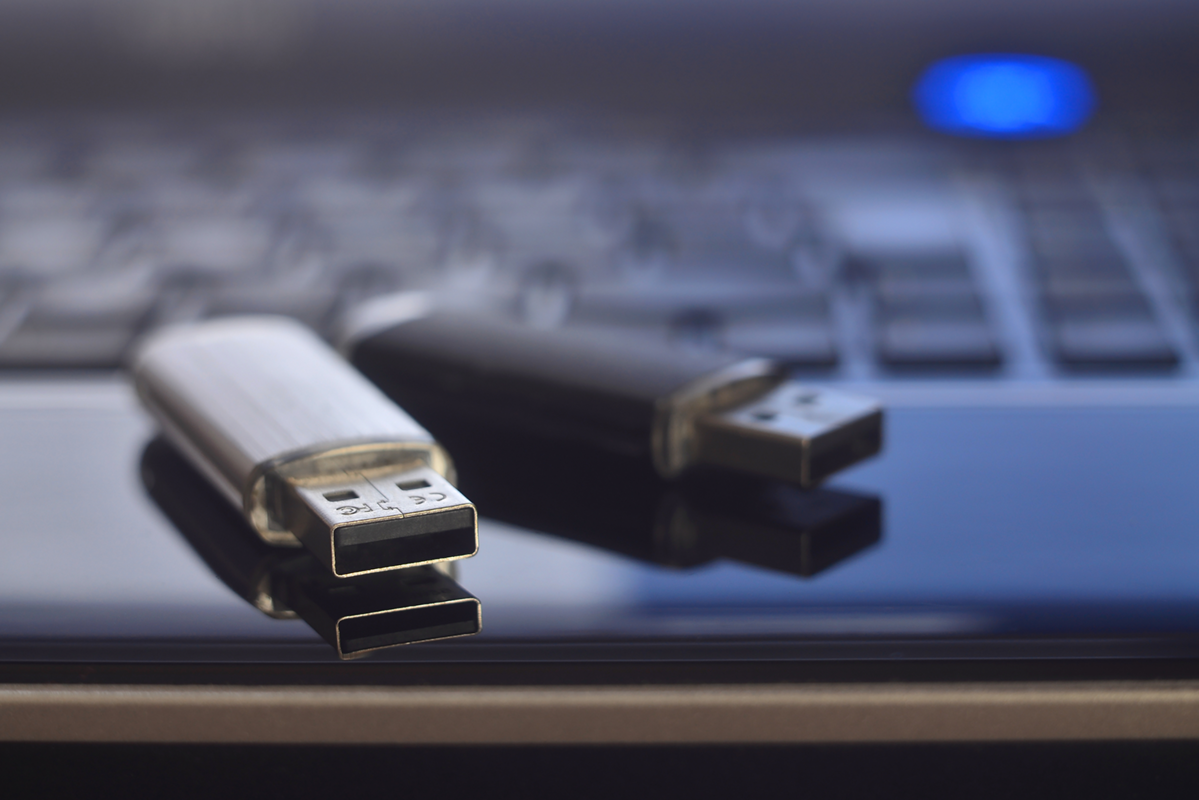 Dva USB flashdisky ležící na notebooku.