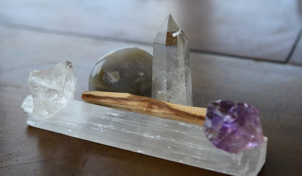 Krystaly křišťálu, ametrin a palo santo na dřevěném stole