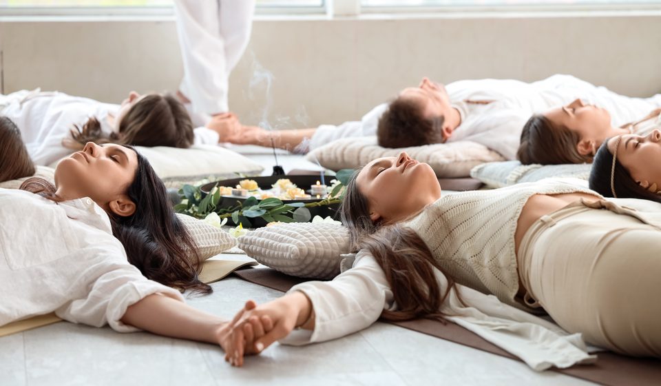 Skupina lidí leží v kruhu při společném breathworku