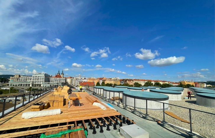 Dřevěná terasa na střeše moderního vlakového nádraží stojí na terčích